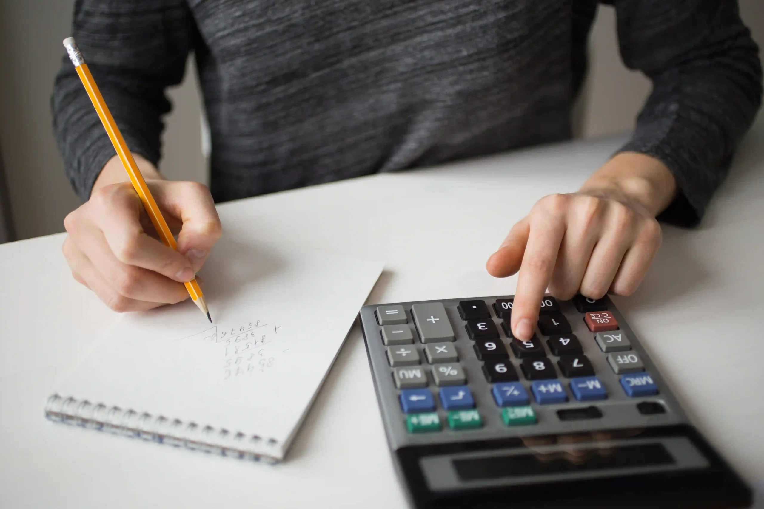 photo closeup of accountant using calculator and writing